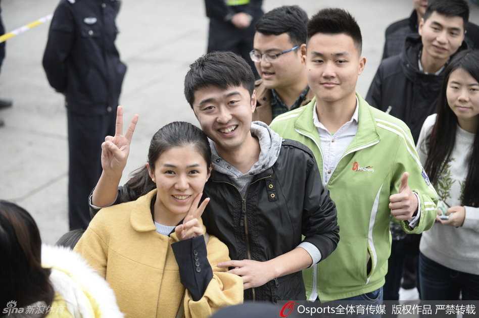 为了抵御深夜的困倦和寒冷，几位球迷席地而坐，其中一人手中拿着手机，或许是在刷新着最新的球票信息，或许是在向未到场的球友直播这壮观的排队盛况。