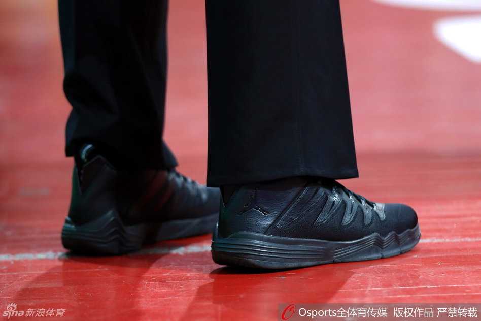 裁判在赛场上专注执法，脚上球鞋的飞人标志在球场灯光下清晰可见，他眼神坚定地盯着场内攻防转换