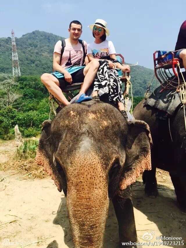 西热力江换上帅气的印花衬衫，与爱妻在一处标志性景观前相拥合影，硬汉的温柔一面展露无遗。