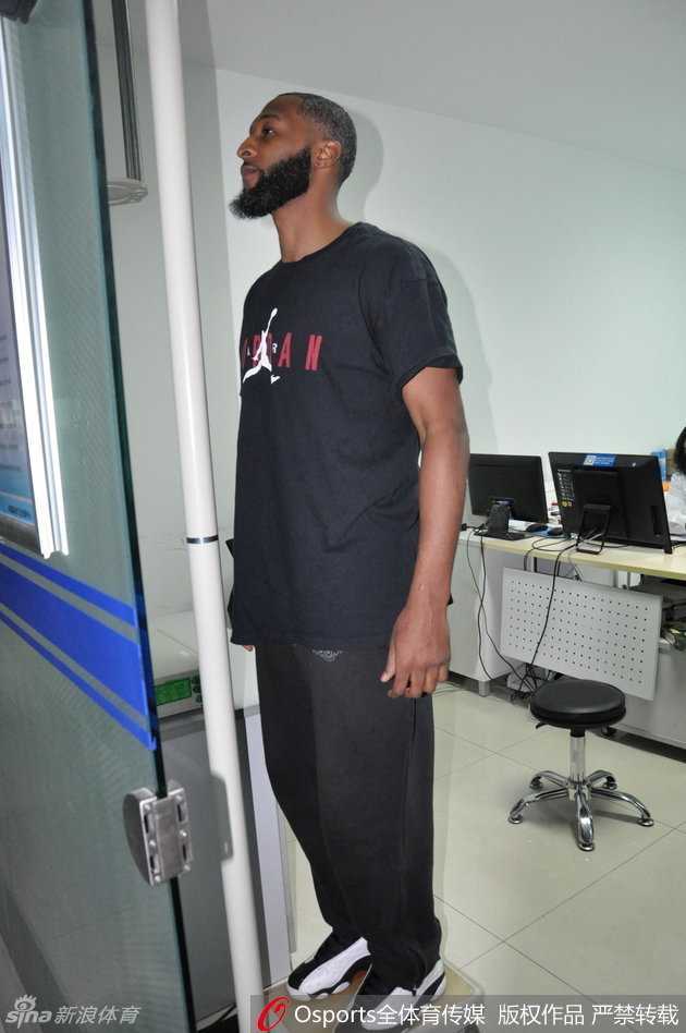 普莱斯正全神贯注地盯着视力表，手指轻轻指向下方，认真的表情如同在比赛中寻找对手防守的破绽。