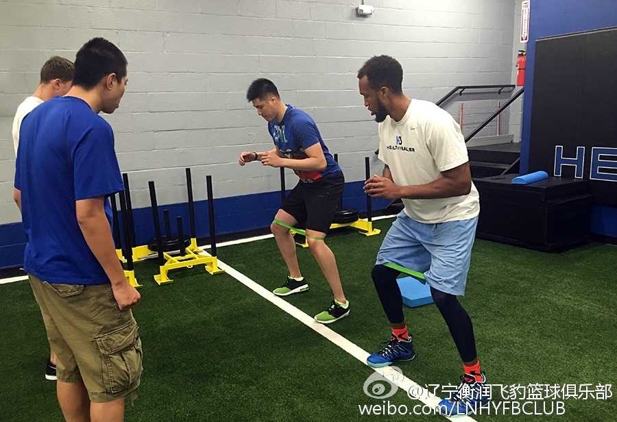 训练馆内的贺天举正在拉伸放松，身后的训练师密切关注着他的肌肉状态，确保在高强度训练后身体能得到最科学的恢复。