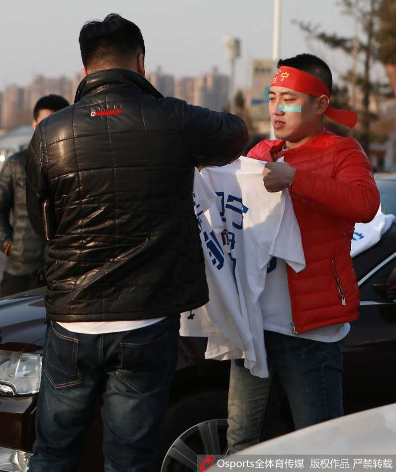 辽沈球迷助威T恤铺满车身,客场远征铸就“第二主场” 在场馆边,几名辽宁球迷兴奋地展开助威T恤,T恤上的球员写真与球迷的笑脸相映成趣,他们正在用最响亮的口号为即将上场的子弟兵打气。