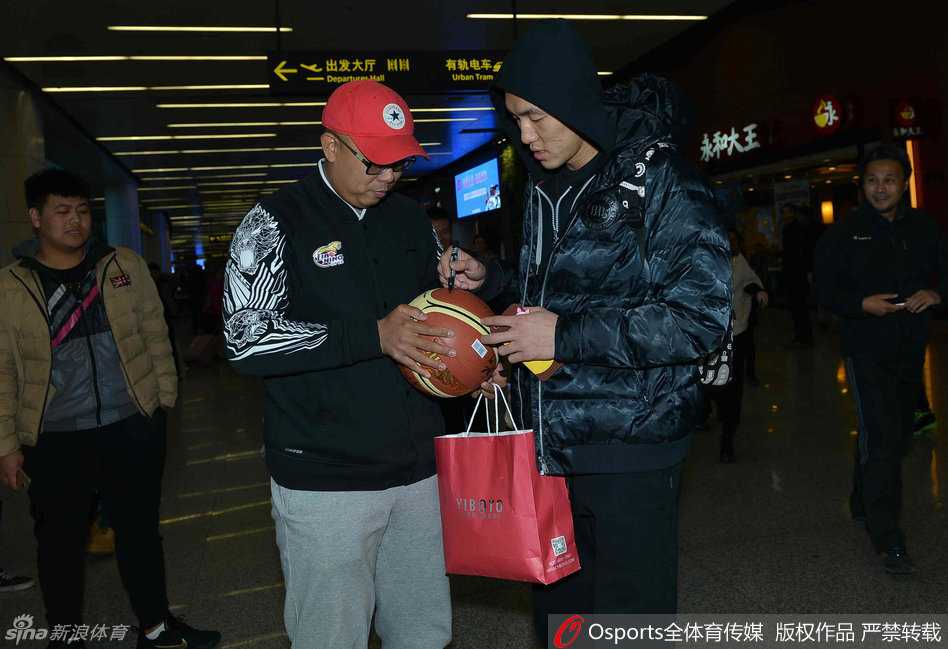 辽篮凯旋日众将暖心互动 郭艾伦杨鸣领衔答谢球迷 郭艾伦面带亲和微笑,俯身为小球迷在辽宁队球衣上签名,周围满是羡慕与喜悦的目光