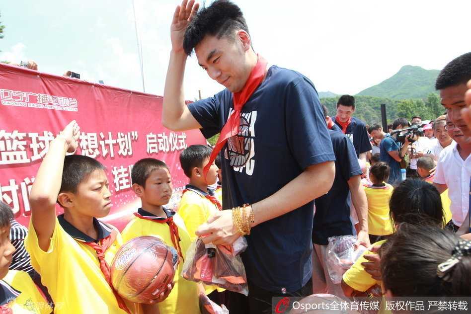 辽篮前锋李晓旭身着运动装，在乡村小学的操场上面对热情的人群，郑重地举手敬礼，眼神中流露出敬意与温情。