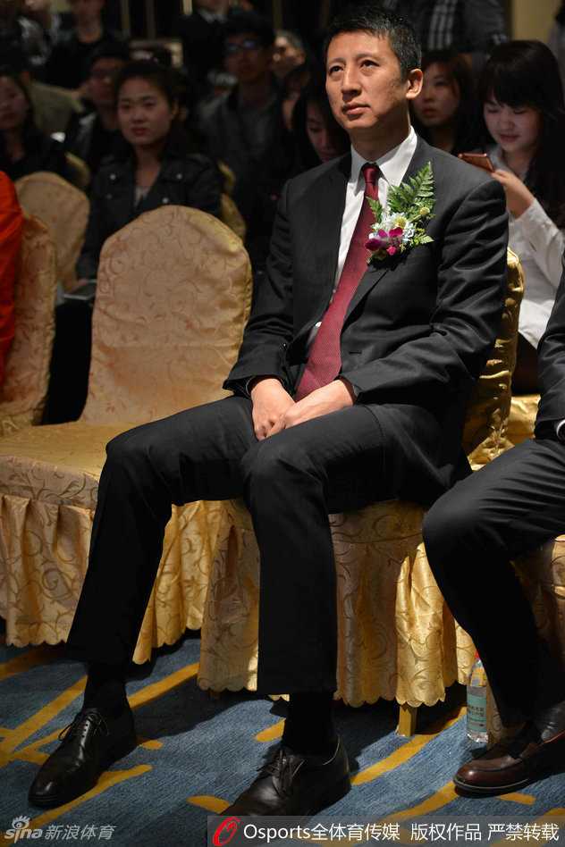 活动现场气氛热烈，郭士强被一群穿着红色T恤的年轻球迷簇拥在中间，他手持签字笔，正侧身倾听一位球迷的提问