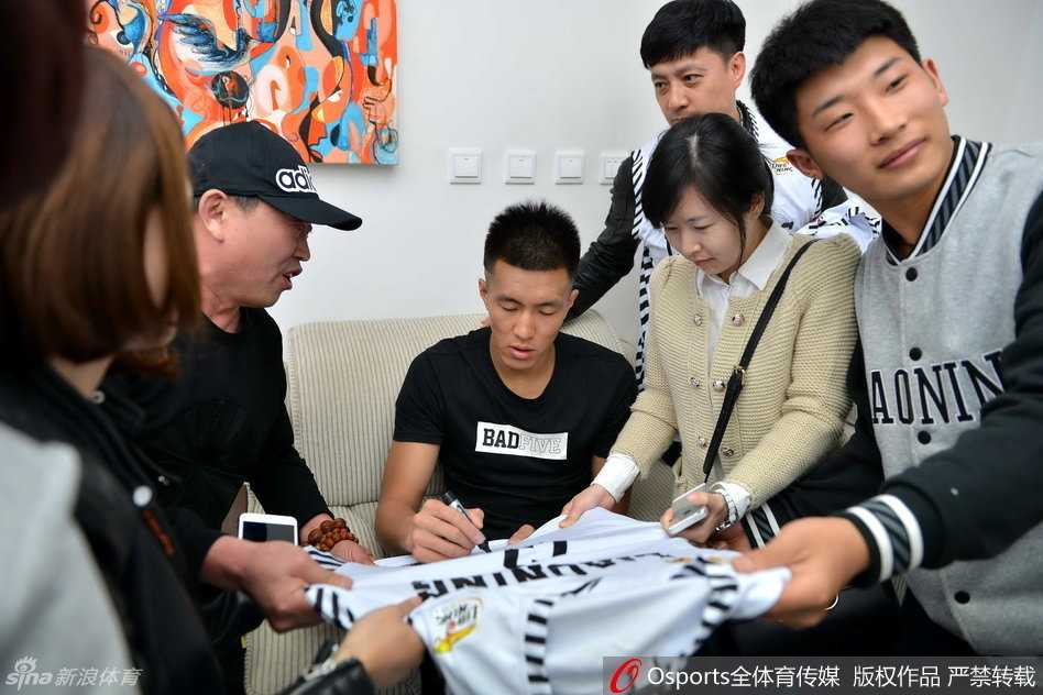 郭艾伦亮相沈阳引爆热情 与女球迷暖心互动大秀球技 郭艾伦坐在休息区的椅子上,耐心地给一位小球迷递过来的球衣签名,他低垂着眼帘,神情专注,小球迷则在一旁紧张又期待地看着。