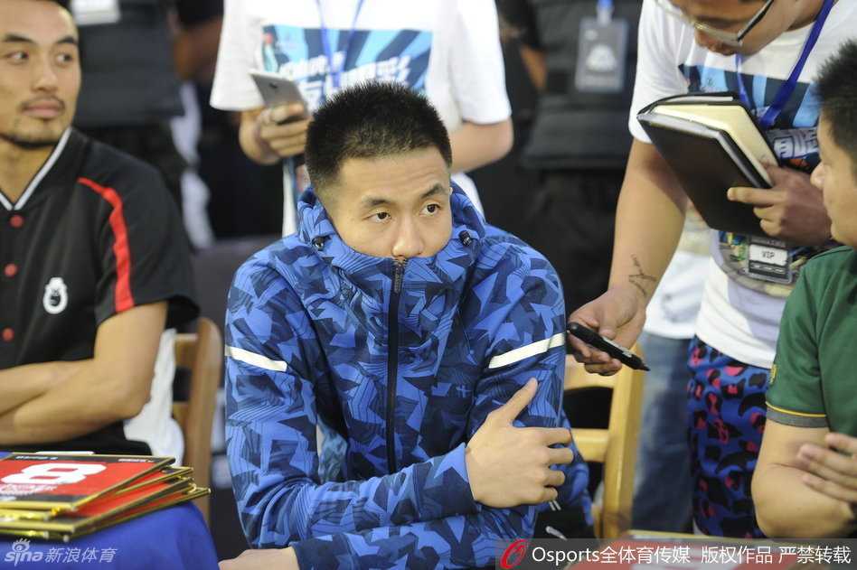 尽管发着高烧身体发冷，郭艾伦依然坐在评委席上，全神贯注地盯着球场上的扣篮大赛，眼神中透露出职业球员的专注与认真。