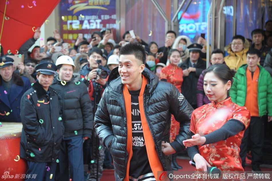 郭艾伦在活动中为球迷签名，他的表情认真而亲切，身后是巨大的品牌背景板，每一个递过来的签名物品他都尽力满足，尽显宠粉本色。