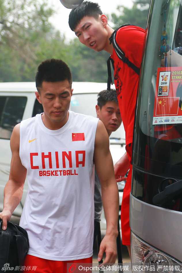 易建联坐在场边休息，目光投向远处正在投篮的年轻队友们，脸上浮现出轻松而欣慰的笑容，仿佛在说：接下来就看你们了。