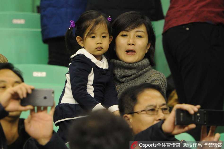 杨鸣妻子唐佳良神情专注地注视着场内，双手合拢放在嘴边，仿佛正在为心中的英雄送出最响亮的应援口号。她的眼中闪烁着对胜利的渴望和对亲人拼搏的心疼。