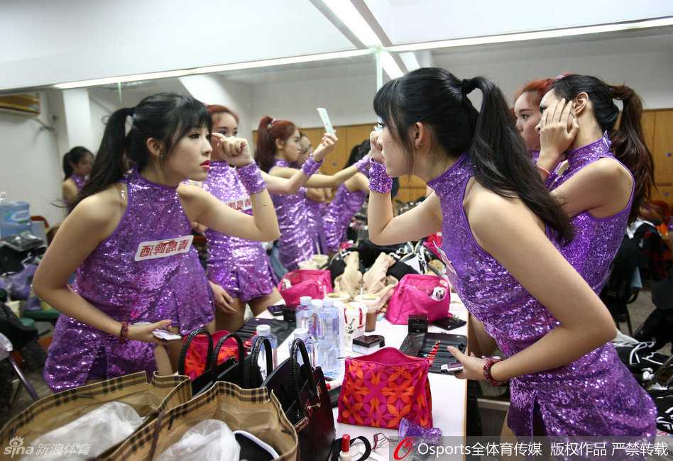 镜头捕捉到了两位宝贝在狭小的更衣室内忘情自拍的瞬间，她们对着手机镜头摆出俏皮的鬼脸，身后的队友则见怪不怪地继续整理着演出服，狭小的空间里洋溢着青春无忧的欢笑声。