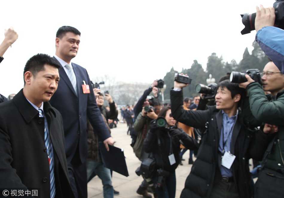 在人群簇拥下，姚明终于迈上了人民大会堂的最后一级台阶，他正准备快步走向安检口，身后的记者们依然不甘心地高举相机，捕捉这难得的历史瞬间。