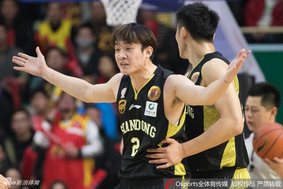 丁彦雨航在对手严防下依然自信出手，篮球在空中划出优美弧线，场边的灯光和观众席虚化背景，定格了这一瞬间的专注与决心