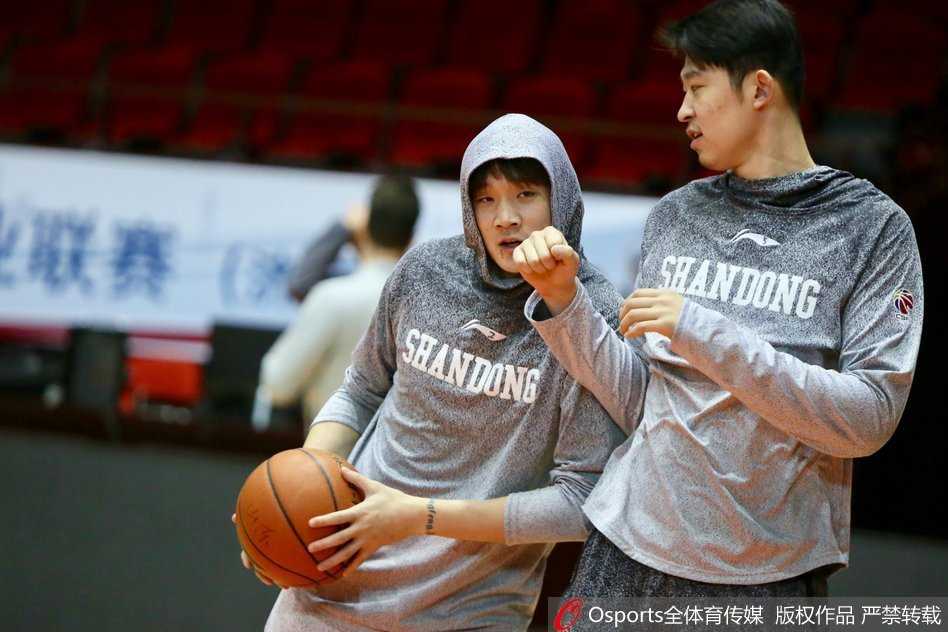 丁彦雨航身穿黑色训练服潇洒走入球馆，脸上带着轻松的微笑，眼神中充满自信。