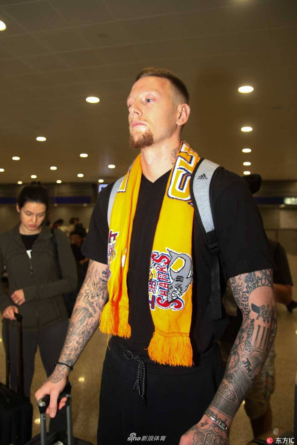 上海大鲨鱼迎新季 重炮明纳拉斯携爱妻空降申城 明纳拉斯在机场接受采访,他手持话筒神情专注而放松,身边的新婚妻子则以温柔的目光注视着他,画面充满了温馨与信任感