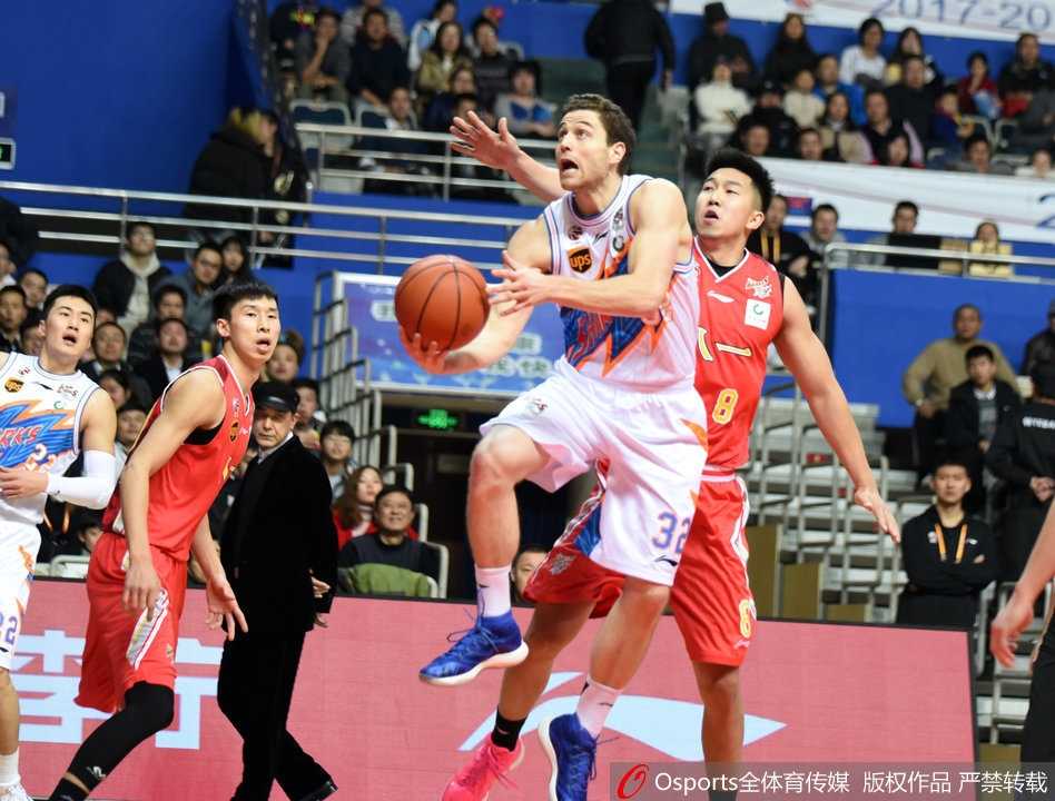 八一队内线悍将付豪在三人合围之下强行起跳上篮，他肌肉紧绷，眼神坚毅，在空中与上海队的防守球员形成激烈的对抗。