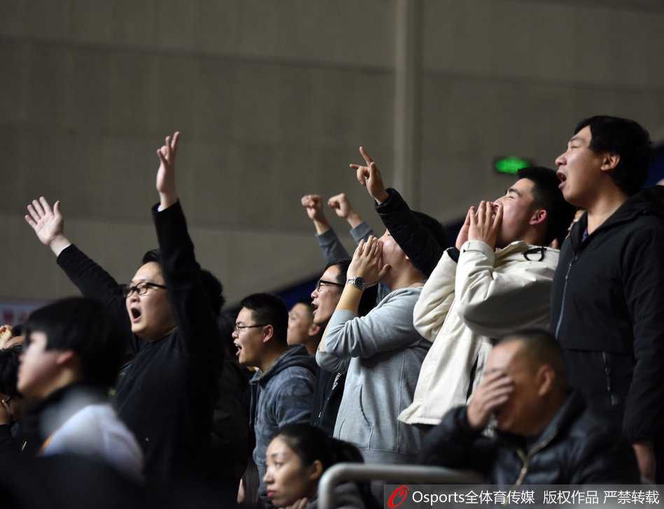 镜头拉近，一位年轻的女球迷脸上贴着上海队的贴纸，双手却高高举着一块平板电脑，屏幕上闪烁着