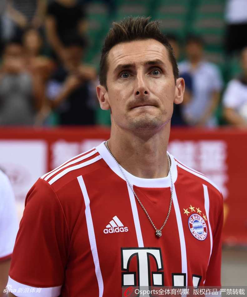 克洛泽与中国男篮队员在场边互动交流，他高大的身影在篮球运动员身边也不显矮小，手势比划着仿佛在讨论刚才的某个精彩进球。