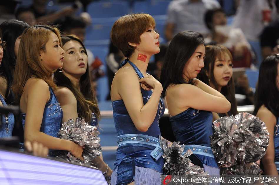 宝贝们身着红白相间的动感队服，侧身凝视镜头，嘴角带着一抹甜美的微笑，修长的身影在球场地板的映衬下格外迷人。