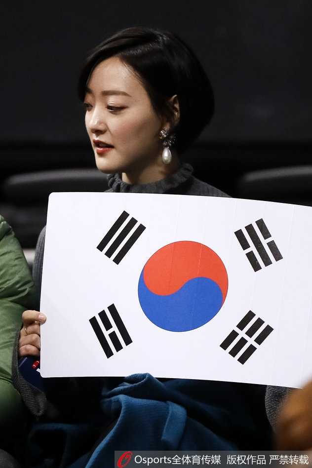 夜幕下的贺龙体育场外，一名女球迷的脸颊上贴着国旗贴纸，她的眼中闪烁着晶莹的泪光，那是对足球最纯粹的挚爱与期盼。