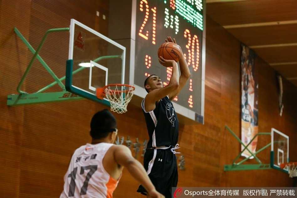 美国高中联队球员如猎豹般敏捷突破防线，高高跃起，试图以一记势大力沉的暴扣撕裂北京五中的防线。