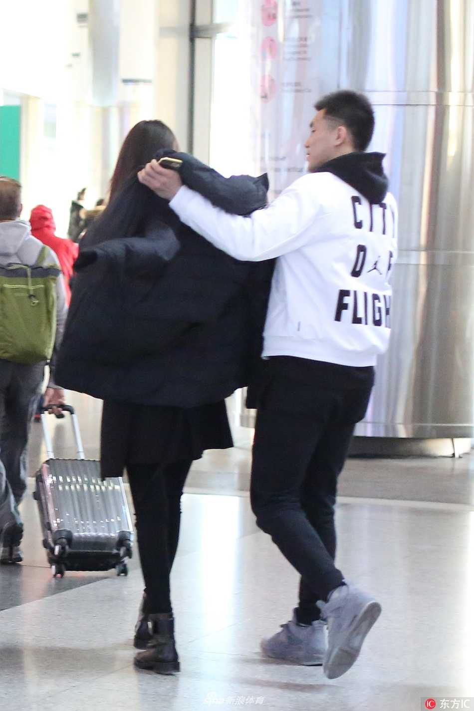 两人在机场大厅中缓慢前行，郭艾伦手中依然拿着东西，时刻关注着女友的步伐，即使只是一个背影，也能让人感受到那份无微不至的照顾与陪伴。