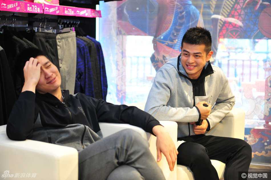 孙悦手拿麦克风正在与现场的球迷进行问答互动，他面带微笑神情轻松，身后的背景板上印有品牌LOGO和活动主题