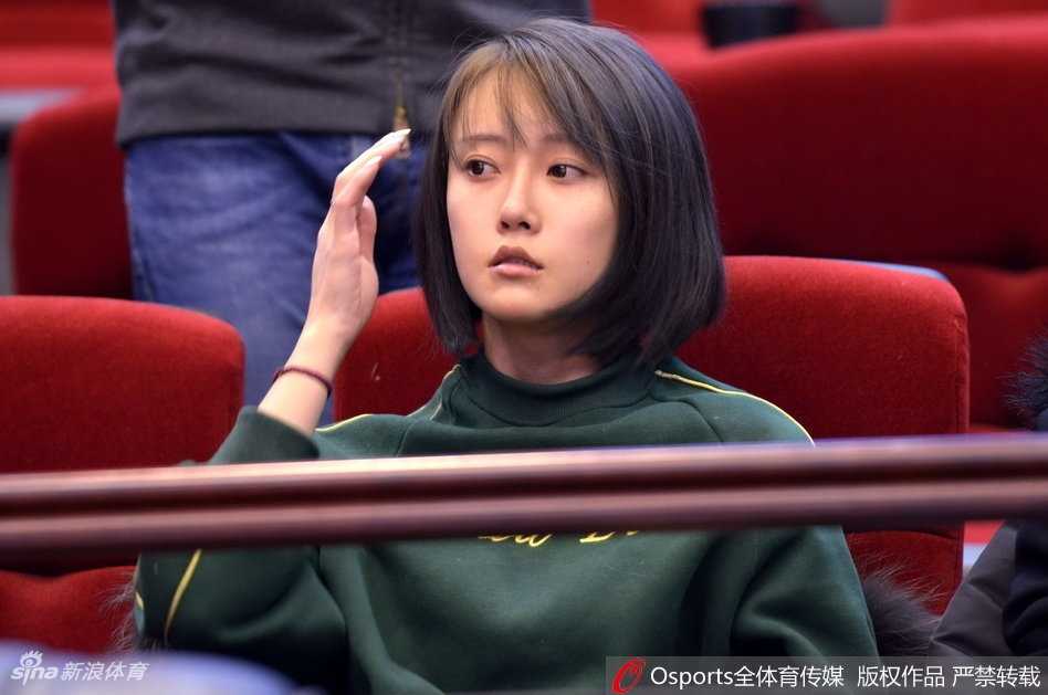 一位戴着可爱毛线帽子的美女球迷，双手放在嘴边作喇叭状，正在全神贯注地呐喊，仿佛要用自己的声音为场上球员注入能量。