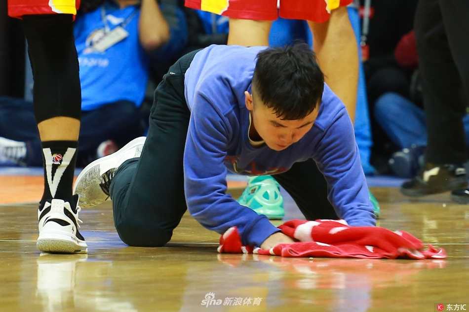 镜头聚焦在孟飞刚擦拭过的地板上，那片区域光亮如镜，反射着球馆顶部的灯光，与周围略显暗哑的木地板形成鲜明对比，见证着他极致工作的成果。