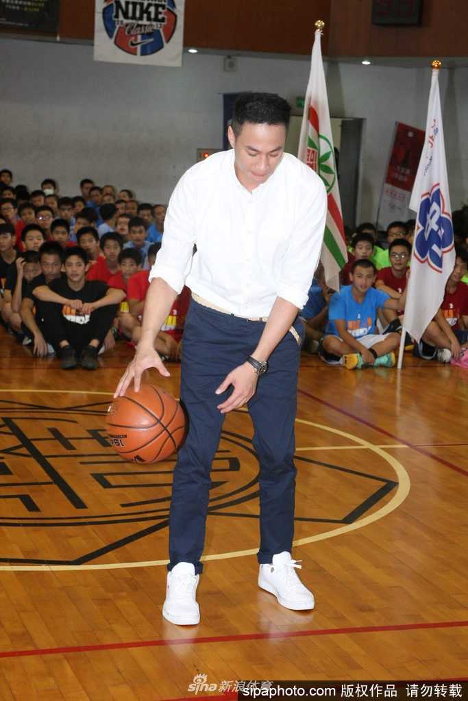 何润东现身中学篮球赛点燃少年篮球魂,八年公益助学延续梦想 球场上何润东运球动作娴熟眼神专注,虽然脚伤未愈但风采依旧,正耐心地为学生们进行示范指导。
