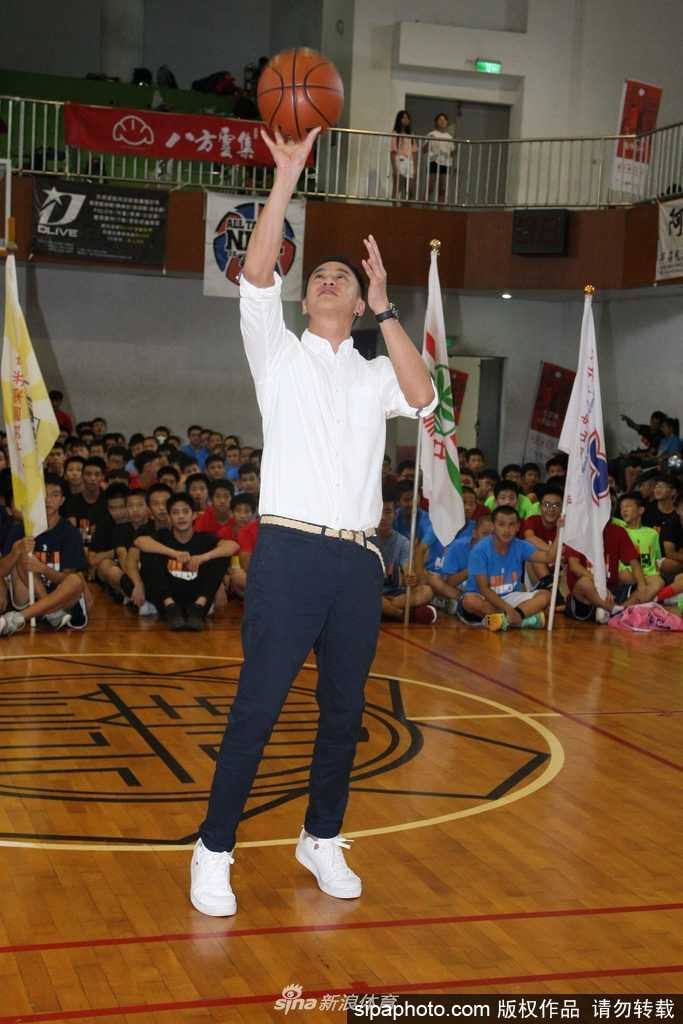 何润东现身中学篮球赛点燃少年篮球魂,八年公益助学延续梦想 活动间隙何润东被热情的同学们团团围住,他亲切地低头与小球员交谈,画面充满了运动与友谊的温暖气息。