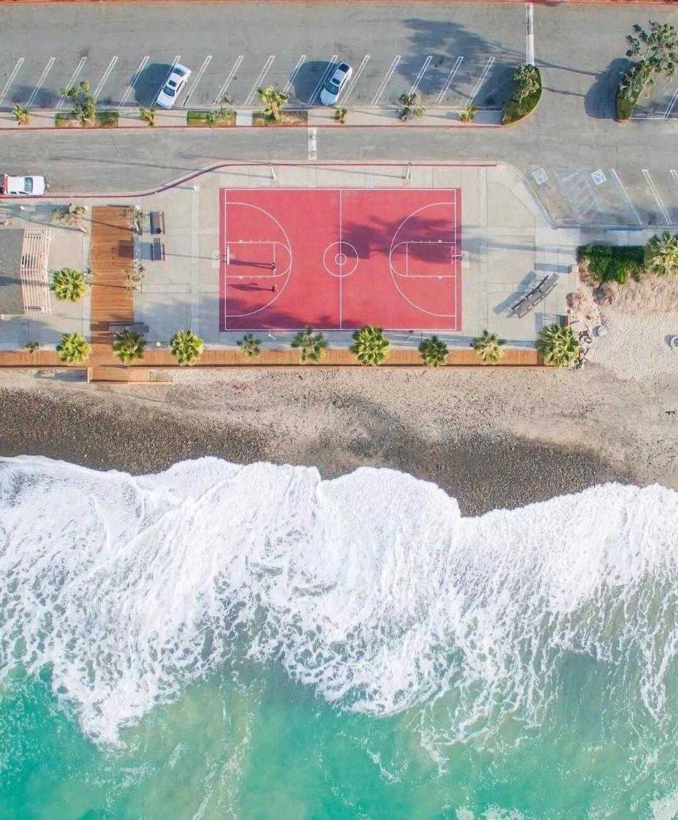 俯瞰光影交错,探寻篮球场的几何诗意 正午阳光直射,篮球场地板上出现清晰的几何阴影区,空无一人的球场在强烈光线分割下,展现出极简主义的冷静美感。