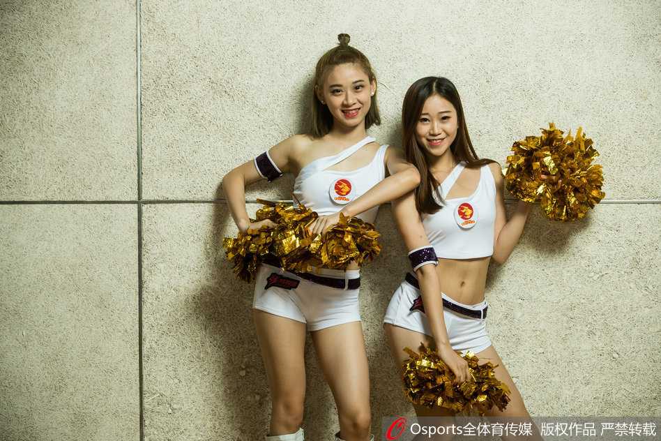 两位篮球宝贝在赛前更衣室内对着镜子互相整理妆容，暖黄的灯光映照出她们认真而温柔的侧脸，幕后准备同样动人