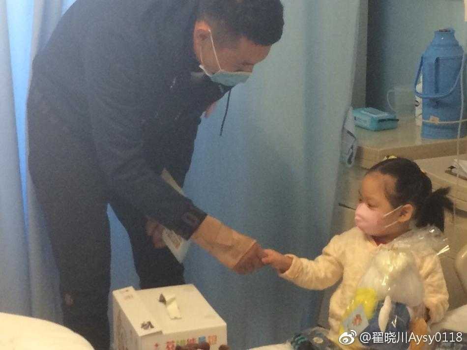 高大的翟晓川将穿着病号服的小朋友轻轻抱起，两人面对面露出灿烂的笑容，如同相识已久的老朋友，彼此眼中闪烁着纯粹的喜悦与信任。