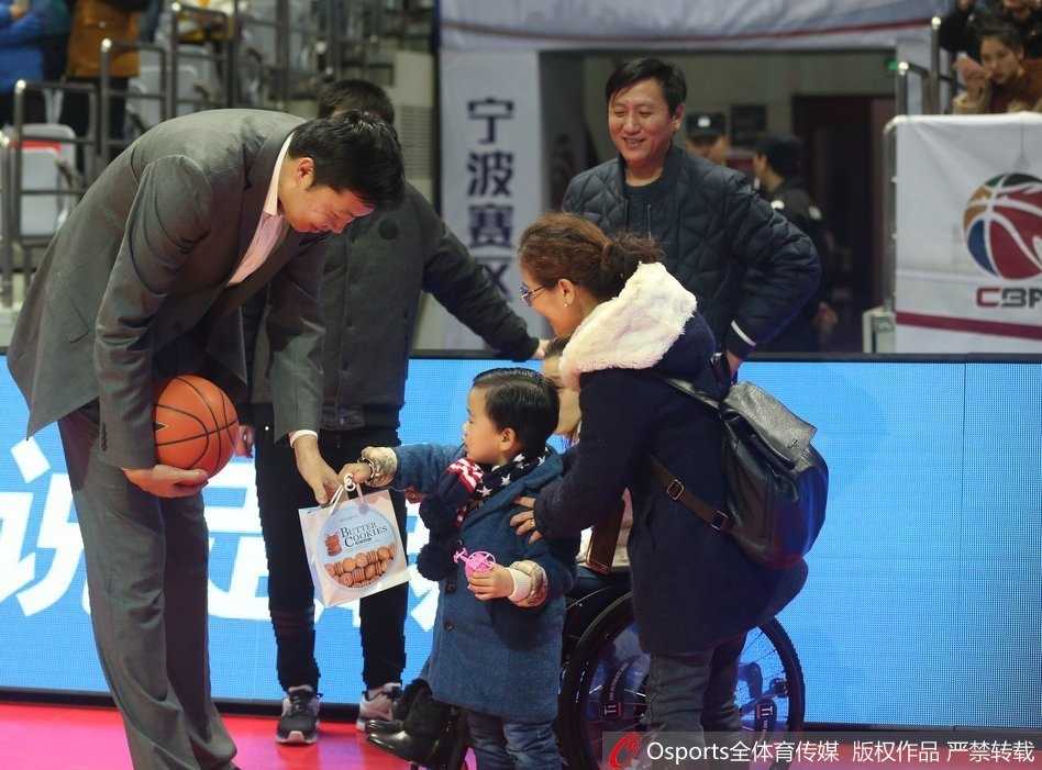 冬日里的温暖邂逅:桑兰携子观战CBA,王治郅赛场送问候 桑兰的儿子身穿可爱的羽绒服,坐在妈妈身边,他回头看向镜头,表情纯真。桑兰的手搭在儿子身上,母子二人与身后巨大的篮球海报相映成趣。