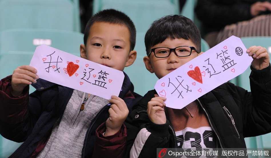 冰火之歌:辽篮主场大胜夜,小球迷暖心上演“真情告白” 全景镜头下,辽宁体育馆内座无虚席,球迷们身穿统一的白色助威服,汇聚成一片白色的浪潮。场地中央,身穿白色球衣的辽宁队员正与身穿深色球衣的福建队员激烈拼抢,现场气氛紧张而热烈。