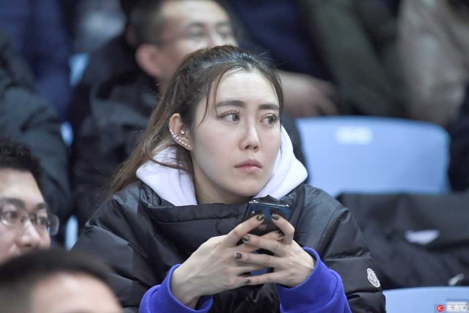 冰雪赛场上的靓丽风景线 吉林女球迷点燃寒冬激情 两名女生凑在一起观看手机屏幕,其中一人身穿灰色大衣,另一人戴着黑框眼镜,两人可能是中场休息时在查看心爱球员的数据,神态专注而亲密