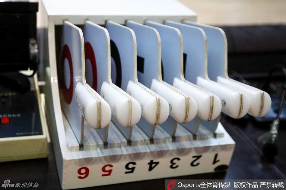 决战前夕的精准脉搏:本溪赛场二十四秒计时器调试全纪实 红色的犯规牌被一只手持握着,准备插入全队犯规显示器的卡槽中,背景是模糊的技术台仪表盘,这抹鲜艳的红色如同警戒线,提醒着即将上场的球员们注意防守动作的尺度。