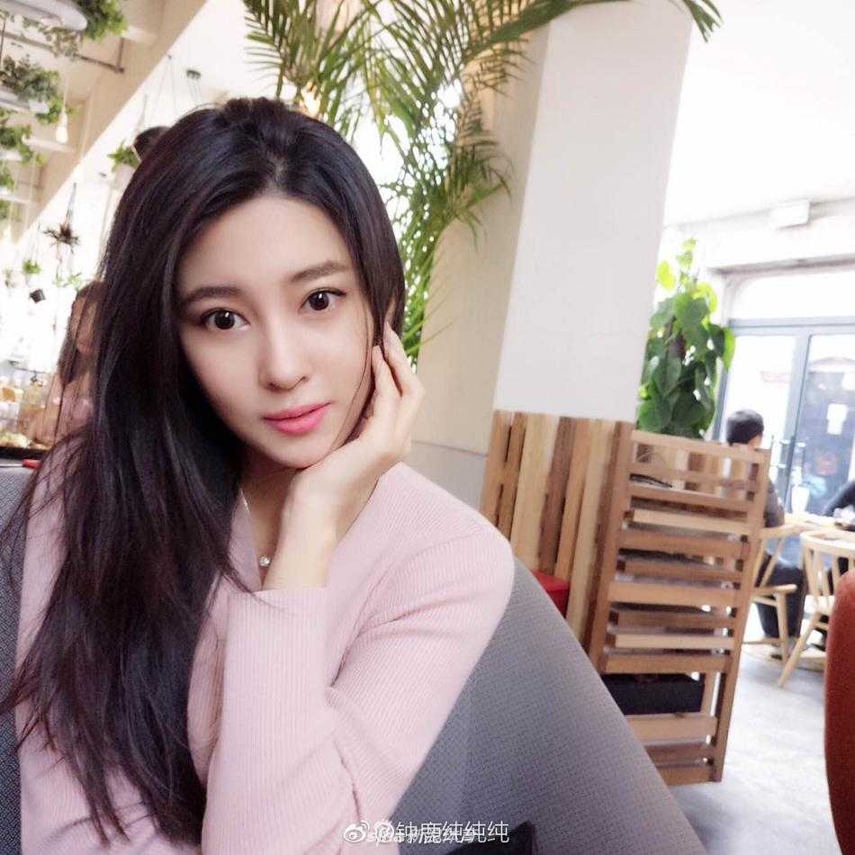 钟鹿纯身穿白色雪纺上衣搭配牛仔短裤，在夏日树影斑驳下，展现出清新甜美的少女感，一双大长腿在阳光下格外吸睛。