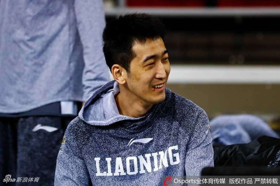 训练结束，韩德君手持篮球，神态轻松地与身边的教练组成员交谈，背景是空旷的体育馆看台，充满了大战前的宁静。