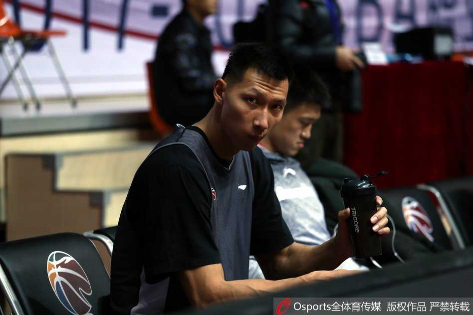 队友在一旁练习运球突破，易建联则站在篮下稍作调整，他拿起放在地上的大号水壶，仰头畅饮，喉结上下滚动，汗水沿着脸颊滑落。