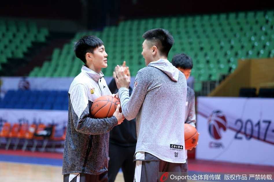 训练进入尾声，易建联赤裸着上身，露出健硕的肌肉线条，他弯腰捡起地上的训练服，准备离场。汗水浸湿了他的头发，折射出场馆内的灯光。