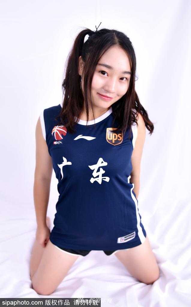 全体篮球宝贝的大合影，她们围绕着球队的旗帜，笑容灿烂，展现出团结一心为广东男篮助威的决心。