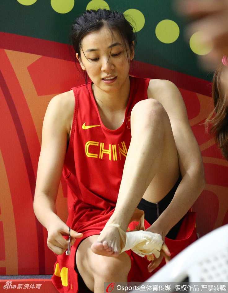 印度备战显从容女篮队员展轻松心态 赵爽正解下身上缠绕的绷带,虽然面露疲惫,但眼神坚定,旁边的队友们三三两两坐在地上进行拉伸放松。