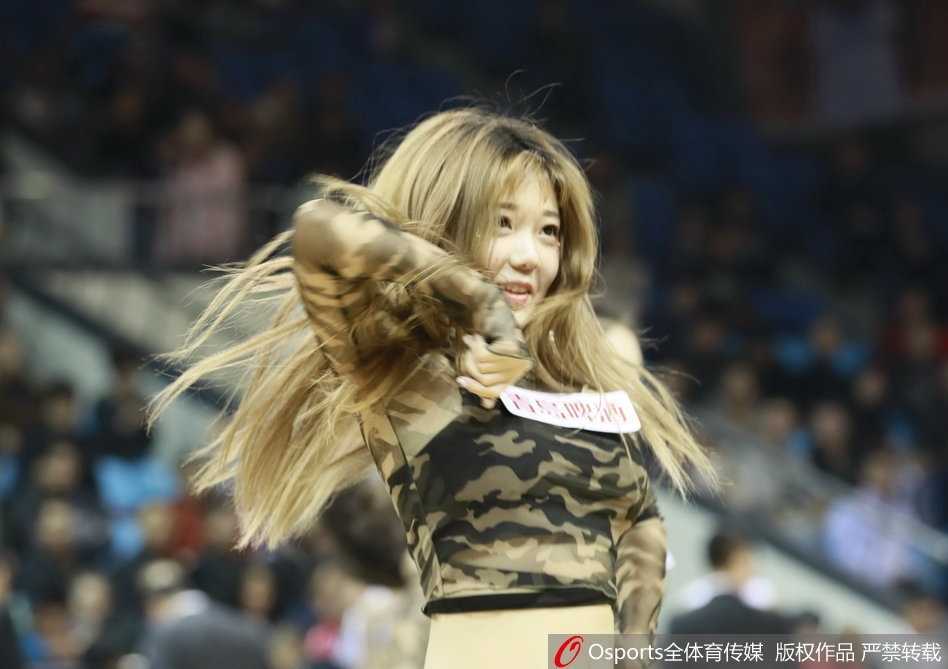 一位篮球宝贝在舞蹈中回眸一笑，红色的裙摆在旋转中飞扬，她的身后是巨大的LED屏幕和翘首以盼的观众，这动人的一幕被相机永远定格。