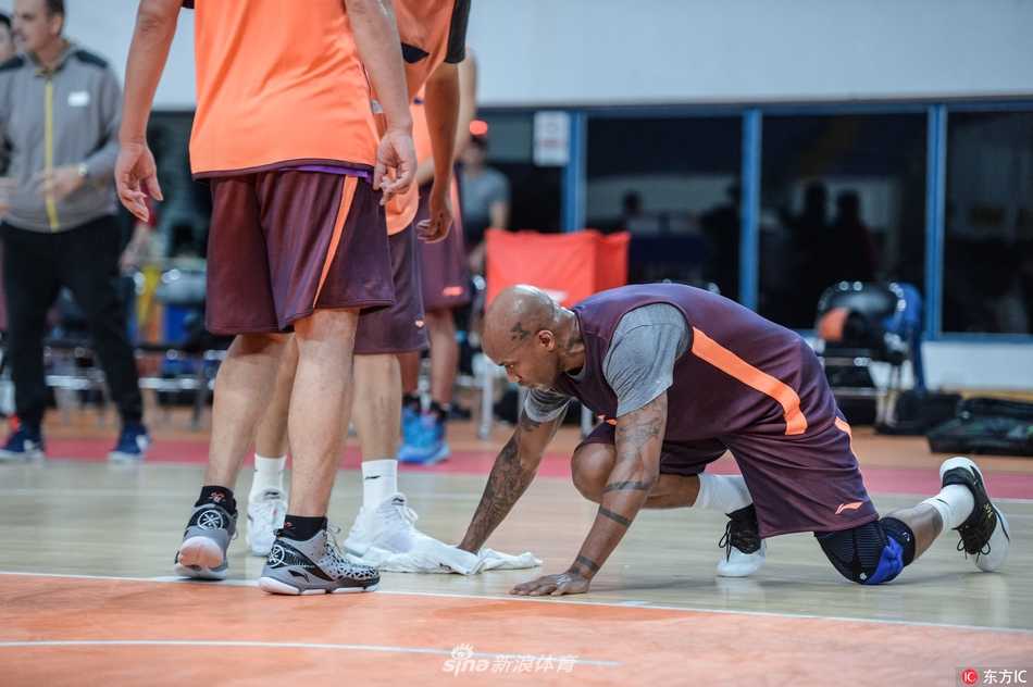 训练馆地板湿滑，老将马布里神情专注，双膝跪在冰凉的地板上，手持白色毛巾用力擦拭水渍，周围是队友们错愕又敬佩的目光。