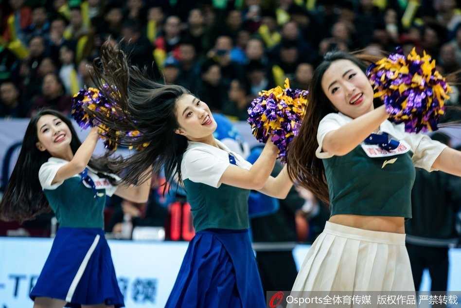 在紫色的灯光背景下，这位宝贝单手叉腰，眼神坚定地注视着前方，金色的亮片上衣在光线下反射出星星点点的光芒，仿佛战场上英姿飒爽的女神。