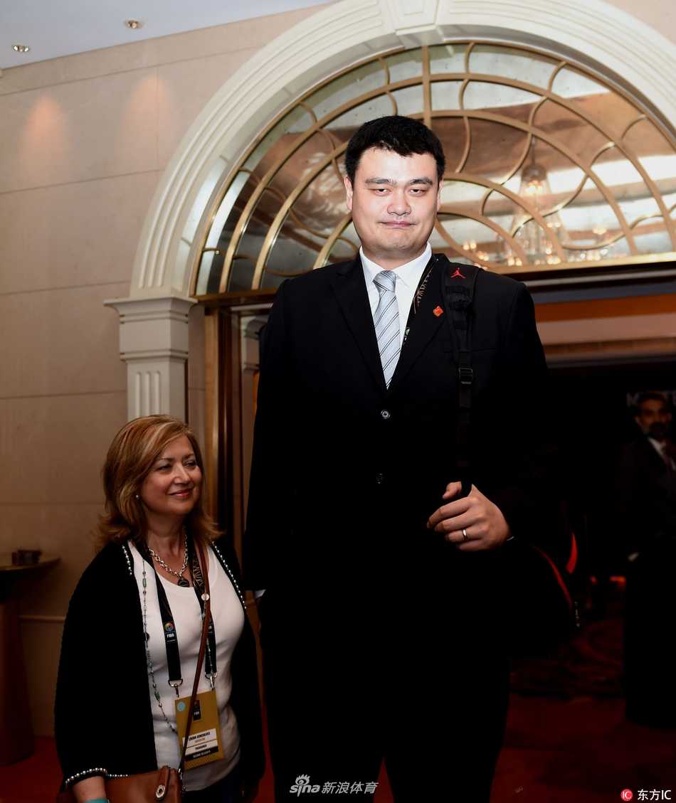 姚明身着深色西装，神情专注地步入会场，他高大的身影在人群中格外突出，周围是各国代表期待与尊敬的目光，仿佛每一步都踏出了中国篮球在国际舞台上的新步伐