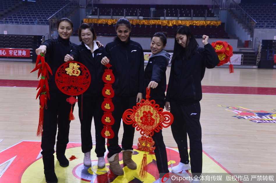 天山玫瑰送新春:新疆女篮的年味与查尔斯的眷恋 王丽丽手持春联,笑容灿烂,身后的队友们凑在一起看向镜头,这幅画面象征着传承与团结,也预示着新的一年球队将焕发新生。