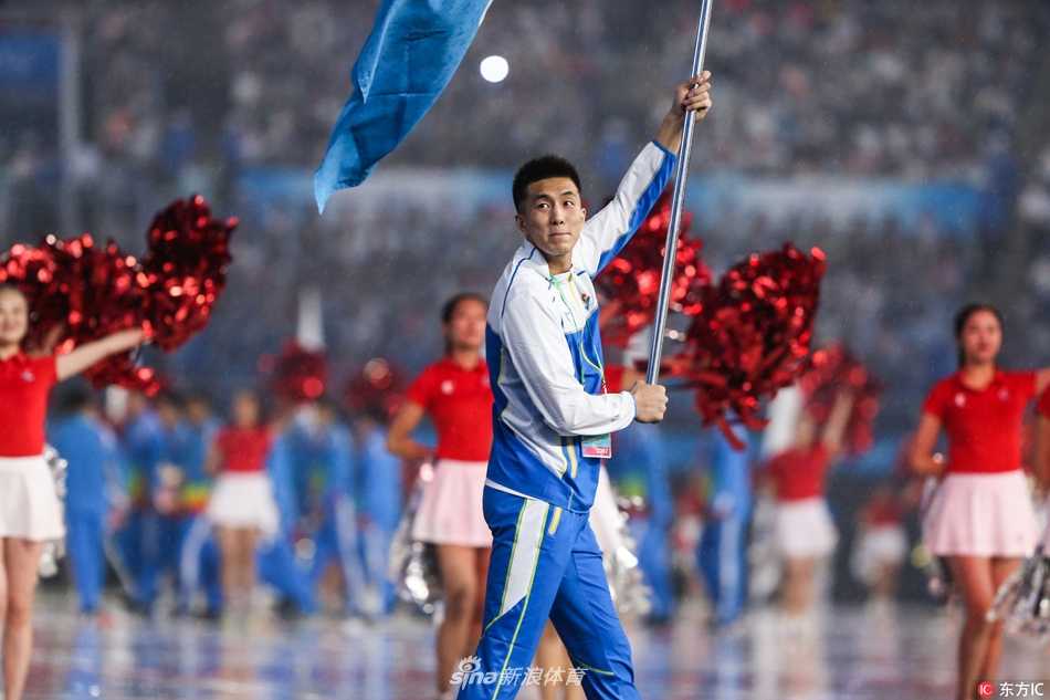 郭艾伦高举辽宁代表团大旗，步入天津全运会开幕式现场，眼神中充满坚定与自豪。